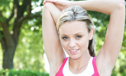 Picture of a woman, happy with her arms liposuction procedure she had with Top Plastic Surgeons in beautiful Cabo San Lucas, Mexico.  The woman is facing the camera with arms outstretched with a backdrop of green trees.