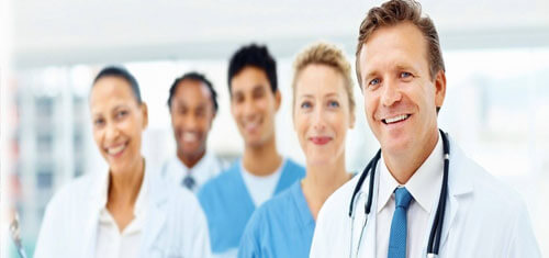 Picture of a doctor representing the top plastic surgeons in Cabo San Lucas, Mexico.  The picture shows a doctor in a white coat standing with 4 members of his staff. 