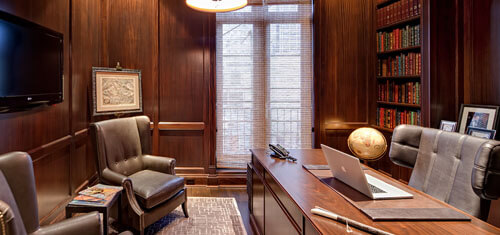 Picture of an office representing the facilities of Top Plastic Surgeons in Cabo San Lucas, Mexico.  The picture shows a beautiful wood finished interior with an executive desk and chairs.