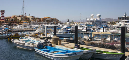 Picture of boats moored in a marina in Los Cabos, Mexico.  The picture shows several small and large boats at the pier on a bright and sunny day..