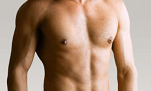Close-up picture of a man,  happy with his male breast reduction  procedure he had in Cabo San Lucas, Mexico.  The man is shown  standing,  to feature his male breast reduction.