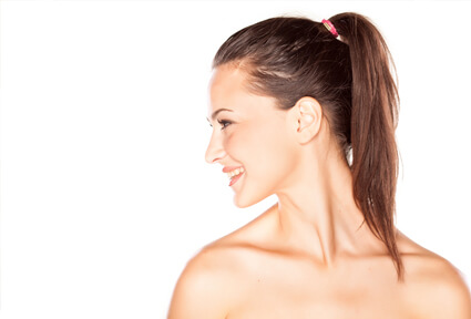 Picture of a woman with long brown hair, slightly turned to the side of the camera and happy with her perfect ear surgery procedure she had with top plastic surgeons in beautiful Cabo San Lucas, Mexico.  The angle of the camera clearly shows one ear.