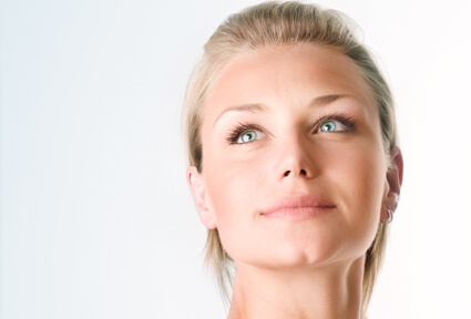 Picture of a woman with blonde hair, facing the camera, and happy with her perfect face lift procedure she had at Top Plastic Surgeons with  top plastic surgeons in beautiful Cabo San Lucas, Mexico.  The woman is looking slightly upwards to show her satisfaction with her face lift.