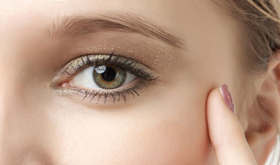 Picture of a woman, facing the camera and happy with her perfect eyelid lift procedure she with Cabo MedVentures in beautiful Cabo San Lucas, Mexico.  The woman has her hand to the side of her face and is pointing to the side of her eye with her index finger.