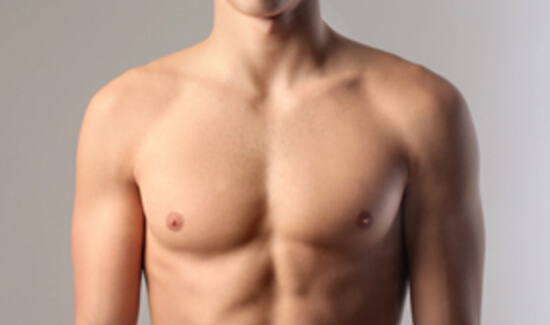 Picture of a man showing his chest and happy with his perfect male breast reduction procedure he had with Cabo MedVentures in beautiful Cabo San Lucas, Mexico.  The man is shirtless and facing the camera and standing against a light purple background.