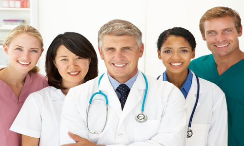 Picture of a smiling medical team representing doctors in beautiful Cabo San Lucas, Mexico.  The picture shows five members of the medical group standing together, facing the camera, and smiling. 